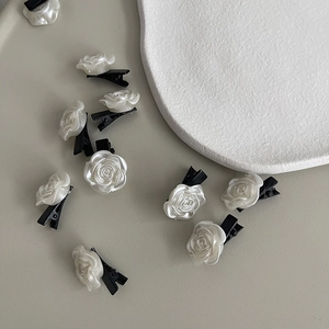 Vue détaillée de mini pinces à cheveux roses blanc perle avec base noire sur fond neutre