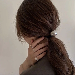 Minimalist silver metal ball hair tie and matching silver rings set on a female model
