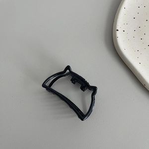 Macro shot of a minimalist black geometric hair claw clip with cat ear shape on grey surface