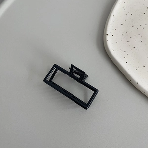 Close-up of minimalist black metal rectangular hair claw clip with hollow frame design