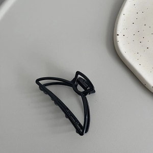 Detail shot of the black matte metal claw clip featuring a minimalist hollow geometric design
