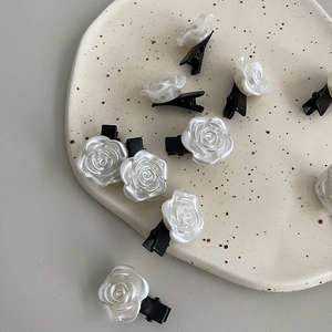 Vue détaillée de pinces à cheveux rose résine blanc nacré avec socle en métal noir
