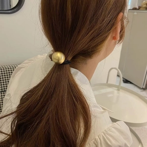 Detailed back view of a high-elastic black hair tie with a brushed gold metal sphere