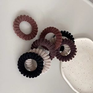 Détail d'élastiques spirales en velours aux tons terreux sur un plateau céramique