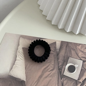 Détail d'un élastique spirale en velours noir dans un décor intérieur minimaliste