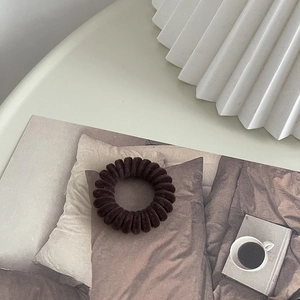 Détail d'un élastique spirale marron foncé floqué avec une texture veloutée
