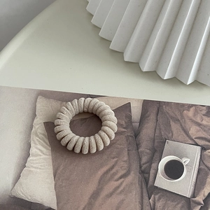 Vue détaillée d'un chouchou spirale floqué beige sur fond de magazine minimaliste
