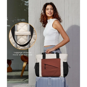 Detailed view of the luggage strap on a quilted travel tote bag for suitcase attachment