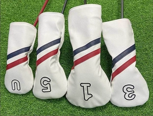 Set di quattro coprimazza da golf bianchi con strisce rosse e blu su erba finta
