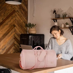 Detail of a pink waterproof travel bag with leather texture and durable handles
