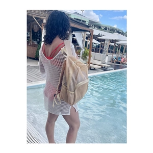 Outdoor shot of beige mesh backpack and white cover-up for beach and pool trips