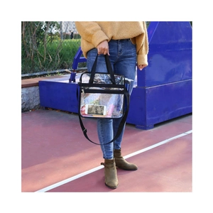 Large transparent PVC travel tote bag with black nylon handles and adjustable shoulder strap