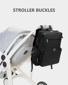 Black waterproof diaper backpack with stroller buckles and gold zippers attached to a stroller