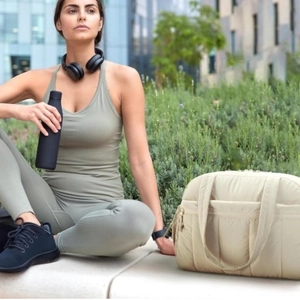 Sac de sport matelassé en nylon pour femme présenté dans un décor de fitness extérieur