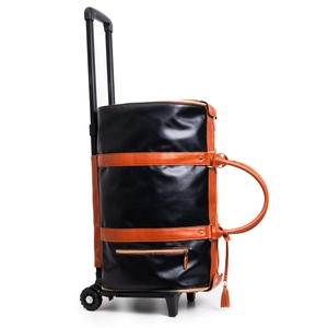 Detail of rolling travel duffel bag in black PU leather with brown straps and wheels