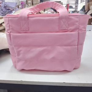 Detail of pink quilted puffer tote showing padded handles and side storage pockets
