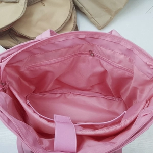 Detailed interior of pink puffy tote bag showing laptop compartment and zipper pocket