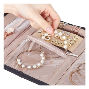 Close-up of pink faux suede travel jewelry roll featuring earring studs and watch storage