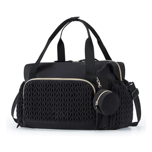 Close-up of the large black travel diaper bag with quilted texture and gold metal hardware