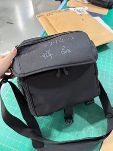 Close-up of a waterproof black camera bag showing multiple zipper pockets and mesh side pouch