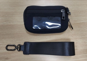 Detail of black waterproof nylon coin purse with ID window and wristlet strap on wood background