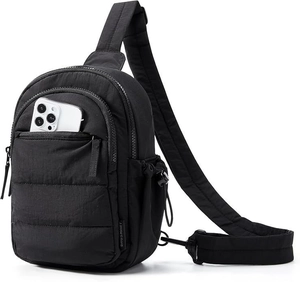 Detail of quilted black crossbody bag with zippered front pocket and side drawstring pocket