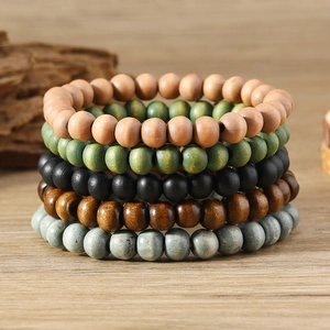 Vertical stack of colorful Bohemian wooden bead bracelets on a natural textured background