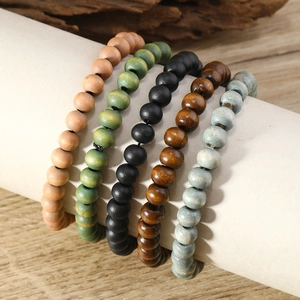 Close-up of bohemian multi-colored wooden bead bracelets on white cylindrical stand