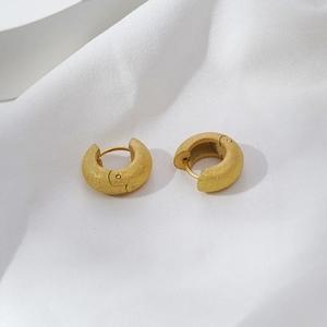 Pair of vintage golden matte stainless steel hoop earrings on white fabric background