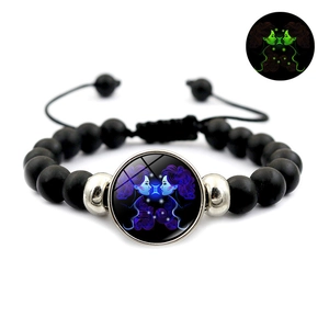 Detailed view of Gemini constellation glowing glass bead on black beaded bracelet