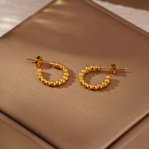 Détail macro de boucles d'oreilles créoles dorées à perles sur boîte de présentation