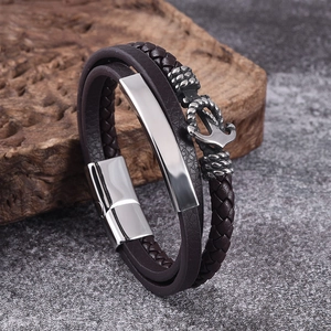 Detail view of brown braided leather bracelet with silver anchor and polished magnetic clasp