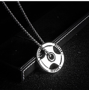 Close-up of silver barbell weight pendant on box chain with industrial metal texture