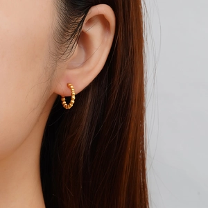 Gros plan de créoles dorées avec texture perlée portées à l'oreille d'un mannequin
