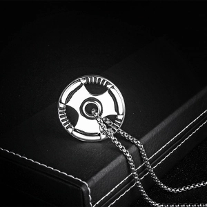 Macro view of a silver barbell weight plate pendant with a box chain on a black case