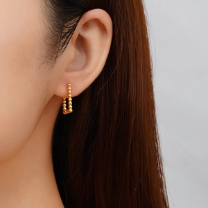 Gros plan de boucles d'oreilles vintage perlées dorées portées par un mannequin