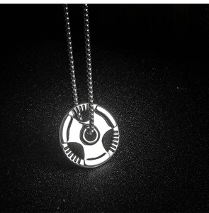 Detail of silver dumbbell plate pendant with bead chain on a dark textured background