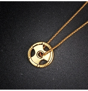 Macro shot of gold barbell weight plate pendant on a sleek square box chain necklace