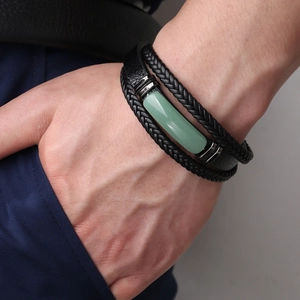 Dettaglio di bracciale multistrato in pelle da uomo con pietra verde al polso
