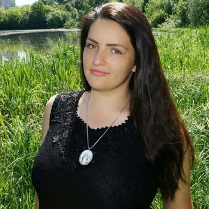 Oval religious pendant necklace on silver chain worn by model in sunny outdoor park setting
