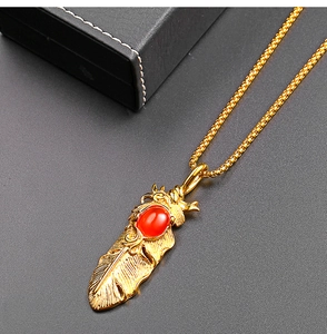 Détail du pendentif plume en acier titane vintage avec pierre rouge sur chaîne dorée