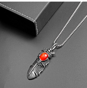 Détail du pendentif plume vintage en acier avec pierre œil-de-chat rouge et textures