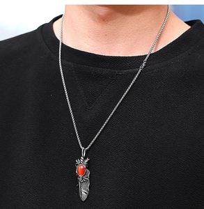 Détail du pendentif plume en argent rétro avec pierre rouge sur une chaîne maille