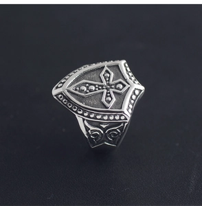 Macro detail of retro shield ring with cross emblem and vintage scroll engravings