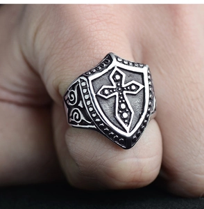 Close-up of vintage titanium steel ring with gothic cross shield design on male hand