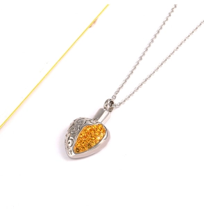 Detail of heart-shaped urn necklace with yellow crystals and vintage scroll patterns