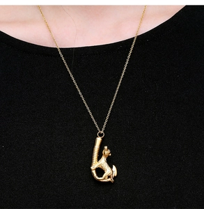 Detailed view of a gold wolf pendant urn necklace for pet ashes on black fabric