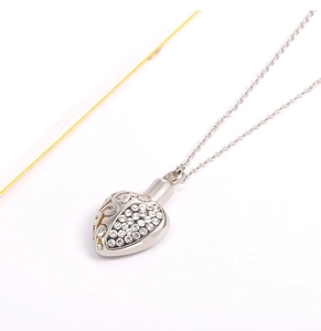 Macro detail of heart urn necklace showing crystal paving and side filigree patterns