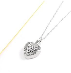 Dettaglio del ciondolo a forma di cuore con pavé di pietre e motivi traforati eleganti