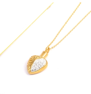 Detailed close-up of a heart-shaped gold perfume pendant with sparkling white rhinestones